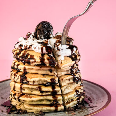 Fork cutting into stack of Oreo pancakes with chocolate drizzle