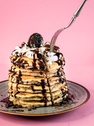 Fork cutting into stack of Oreo pancakes with chocolate drizzle