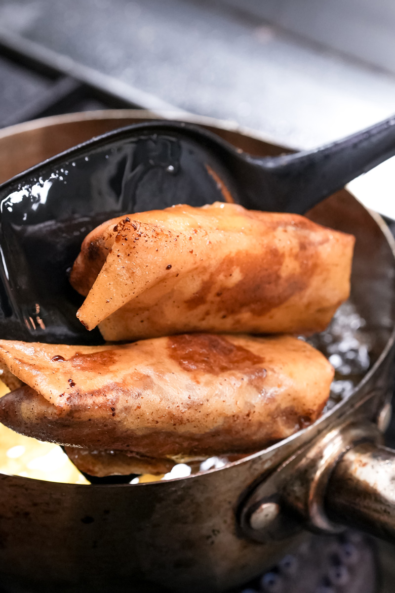Pan-frying banana lumpia in black skillet