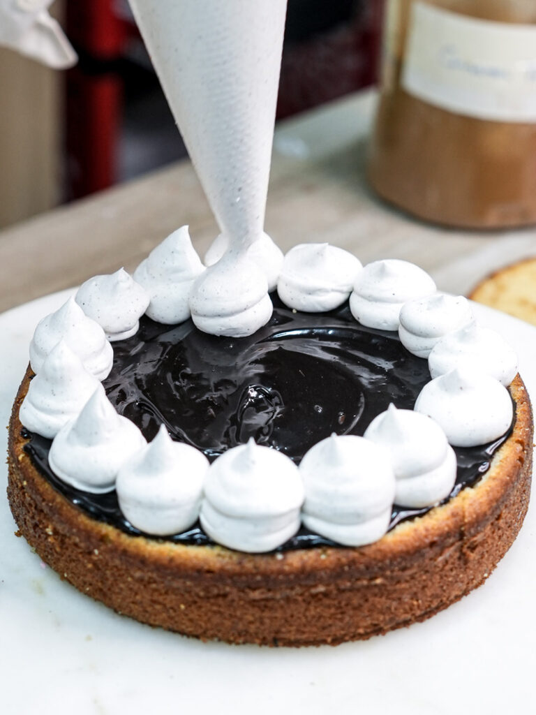 Piping white cream filling onto chocolate ganache churro cake layer