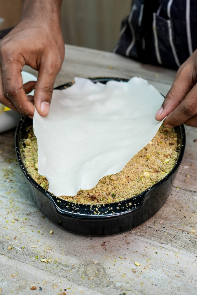 Placing phyllo dough over baklava nut filling