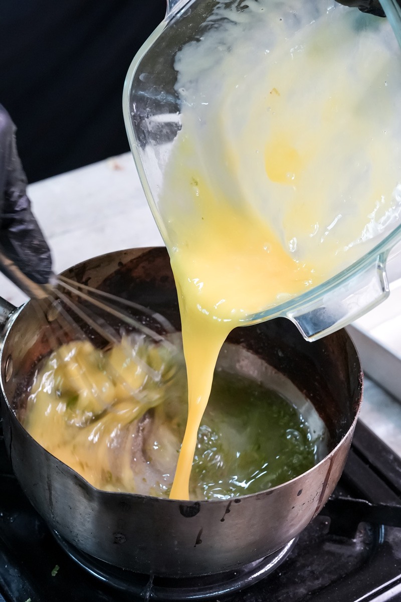 Pouring beaten egg yolks into lemon mixture for lemon curd recipe
