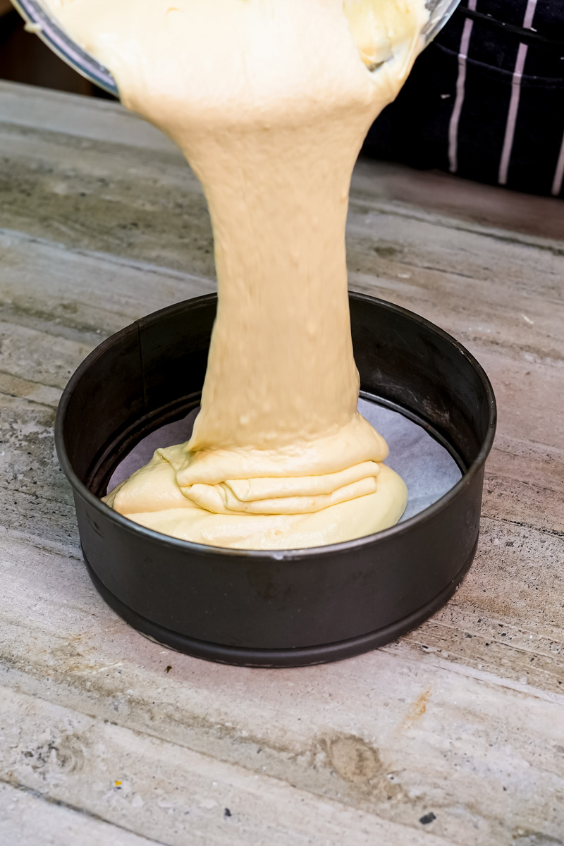 Pouring citrus cake batter into round baking pan