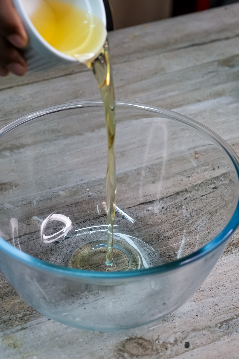 Pouring oil into bowl for mango muffin wet ingredients