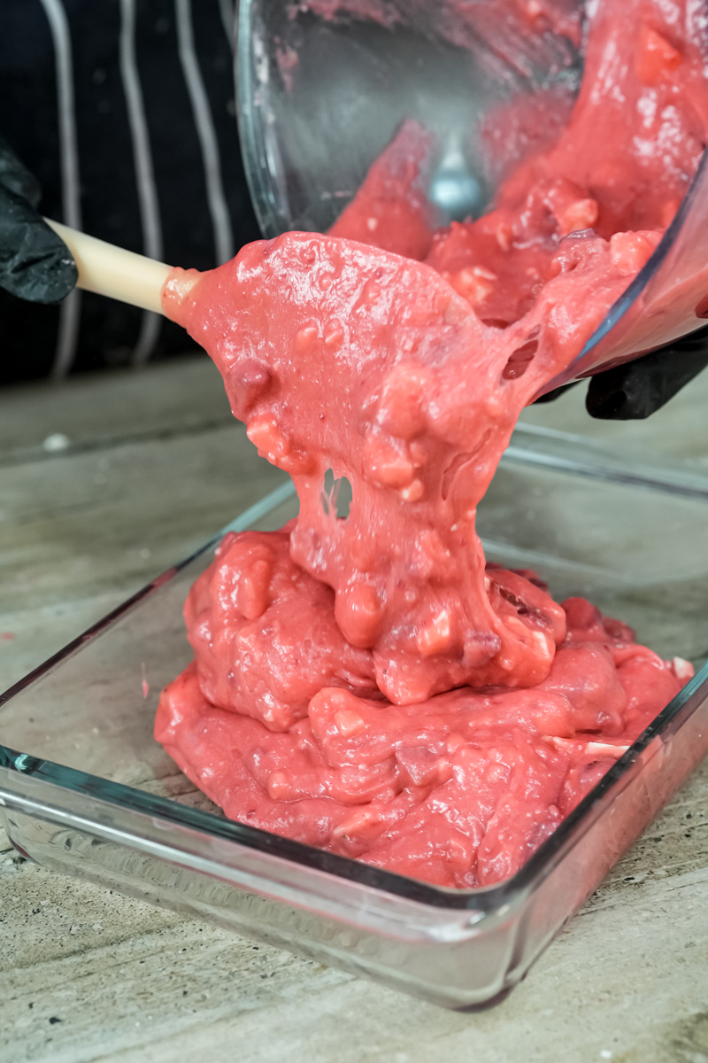 Pouring pink strawberry earthquake cake batter into baking dish