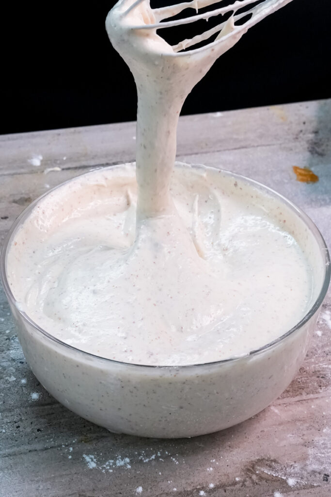 Pouring sifted opera cake batter between mixing bowls