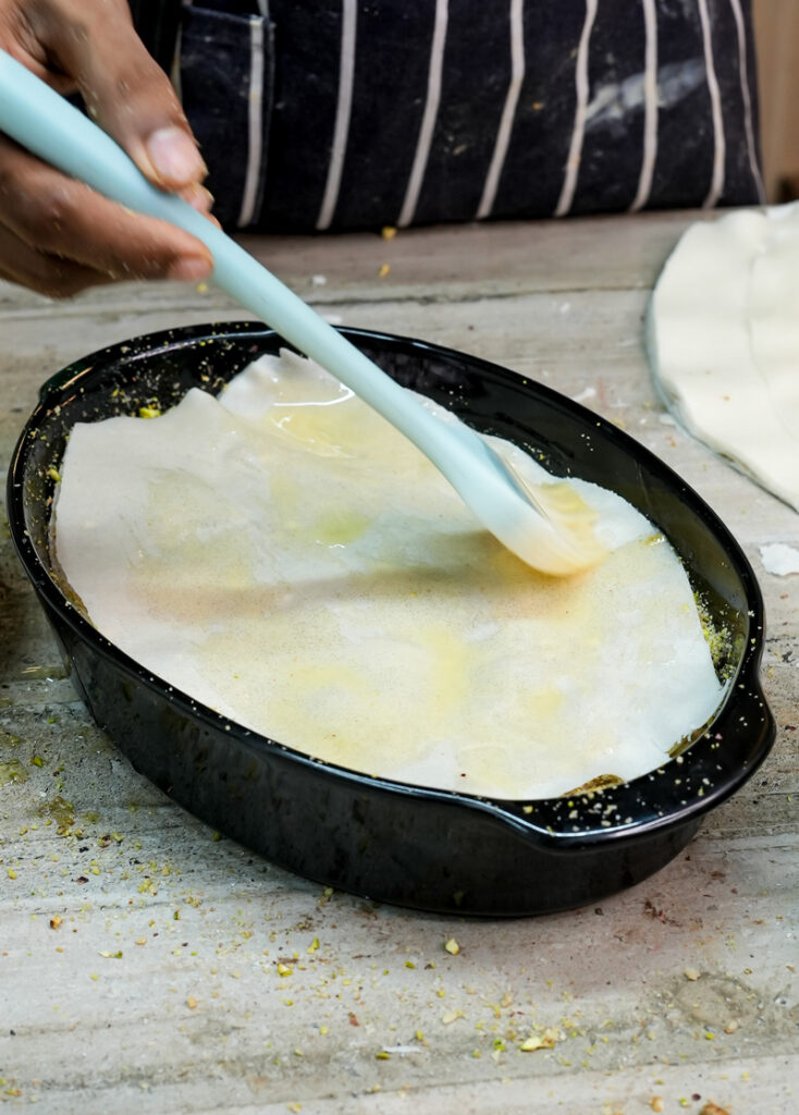 Pouring syrup over baklava phyllo layers