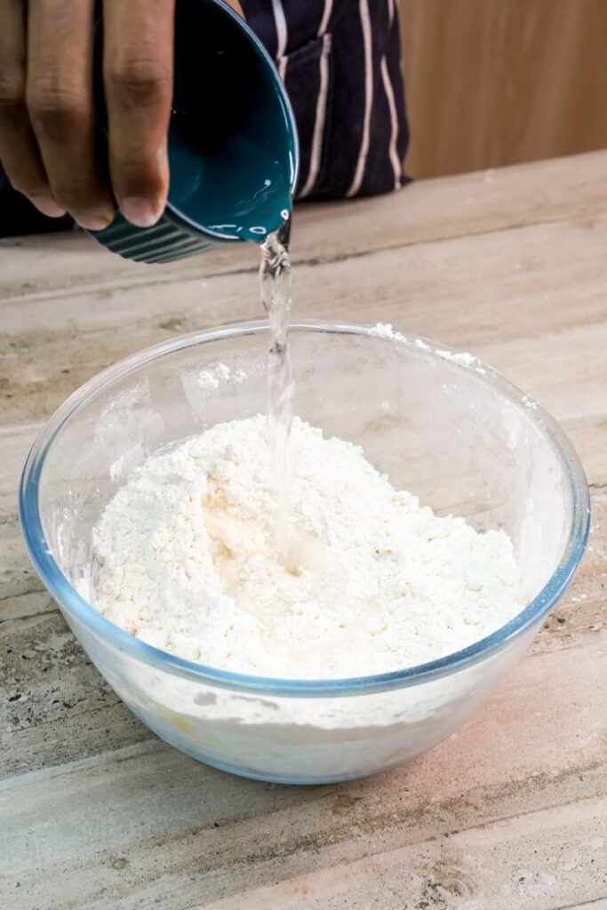Pouring water into empanada dough mixture