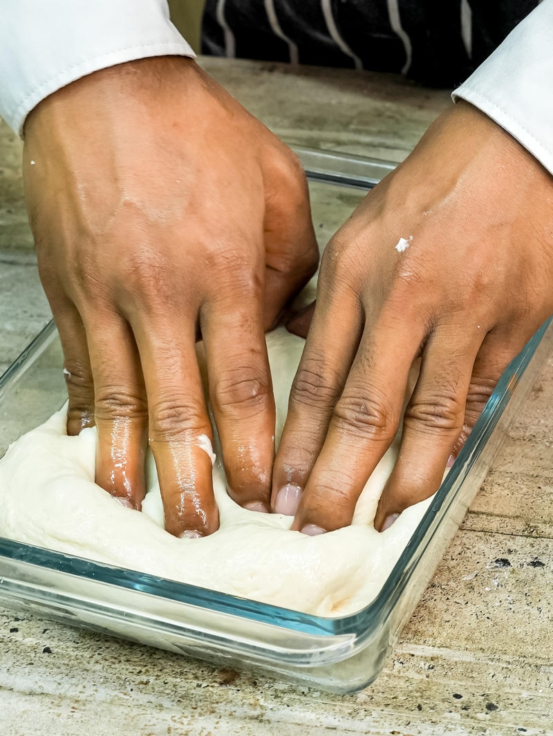 Pressing focaccia dough into baking dish