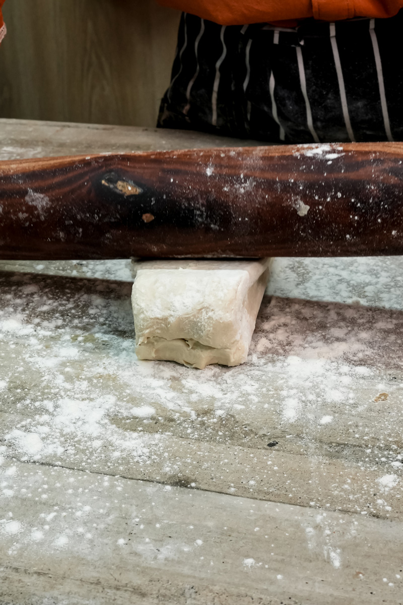 Puff pastry dough being kneaded on floured surface