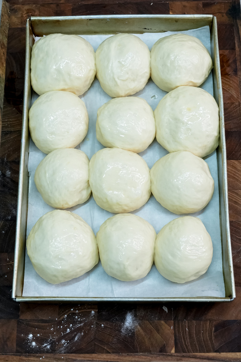 Raw buns arranged on baking tray before rising