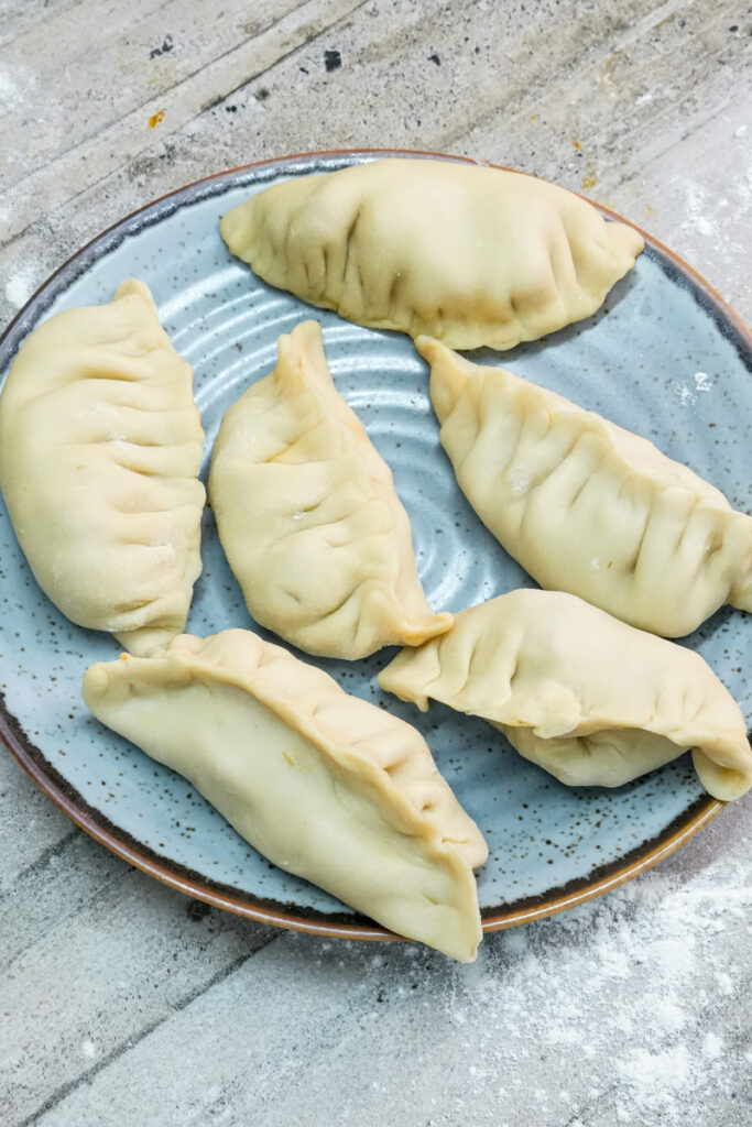 Raw chicken empanadas on blue plate before baking