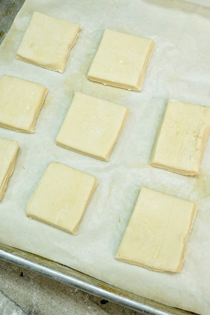 Raw puff pastry squares arranged on parchment paper