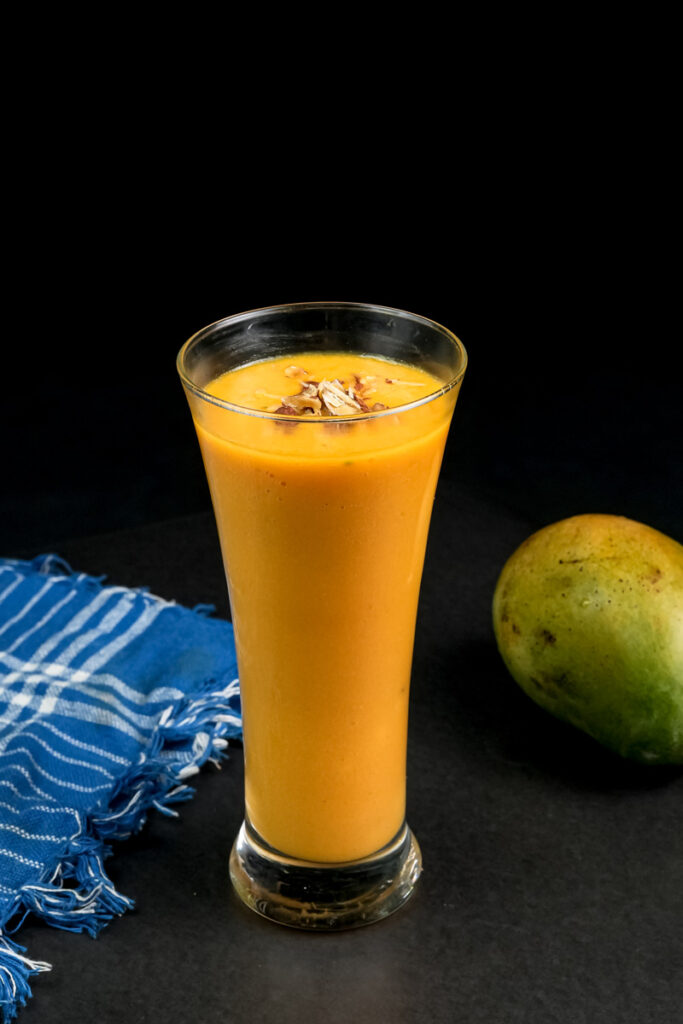 Refreshing mango milkshake with straw and fresh mango