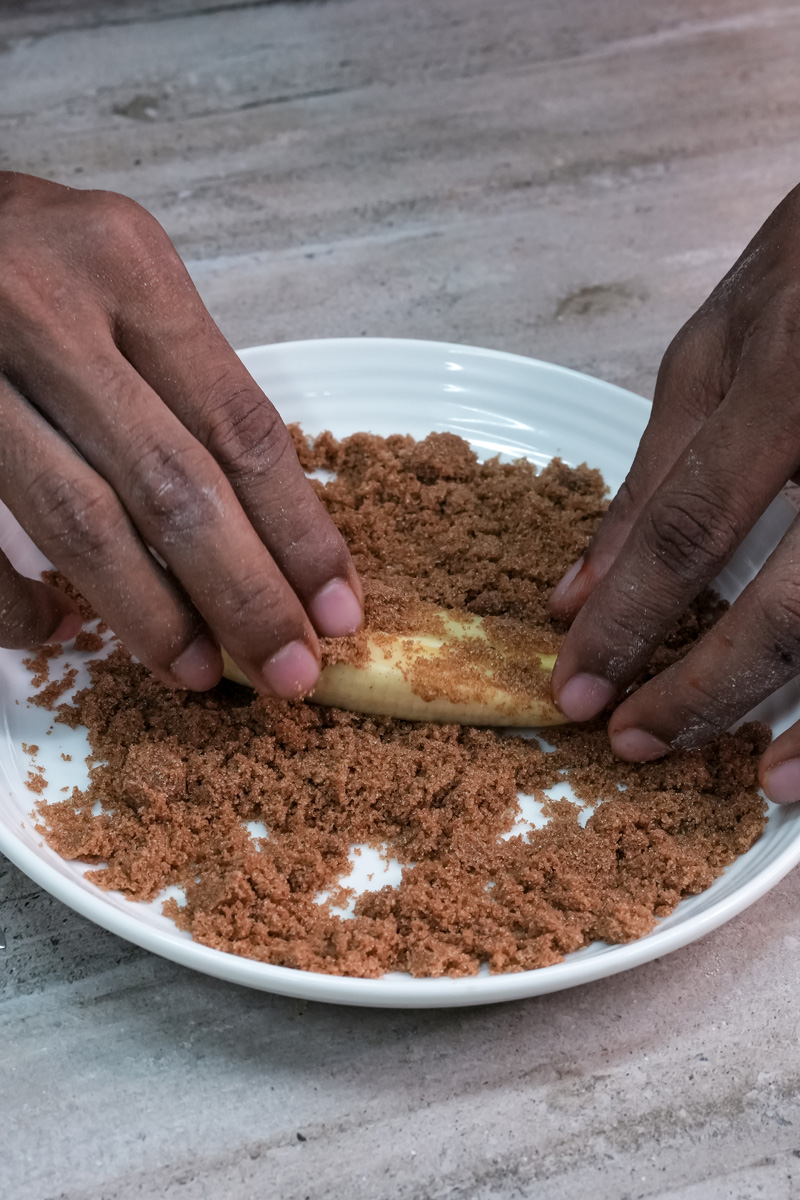 Rolling banana slices in brown sugar mixture for lumpia