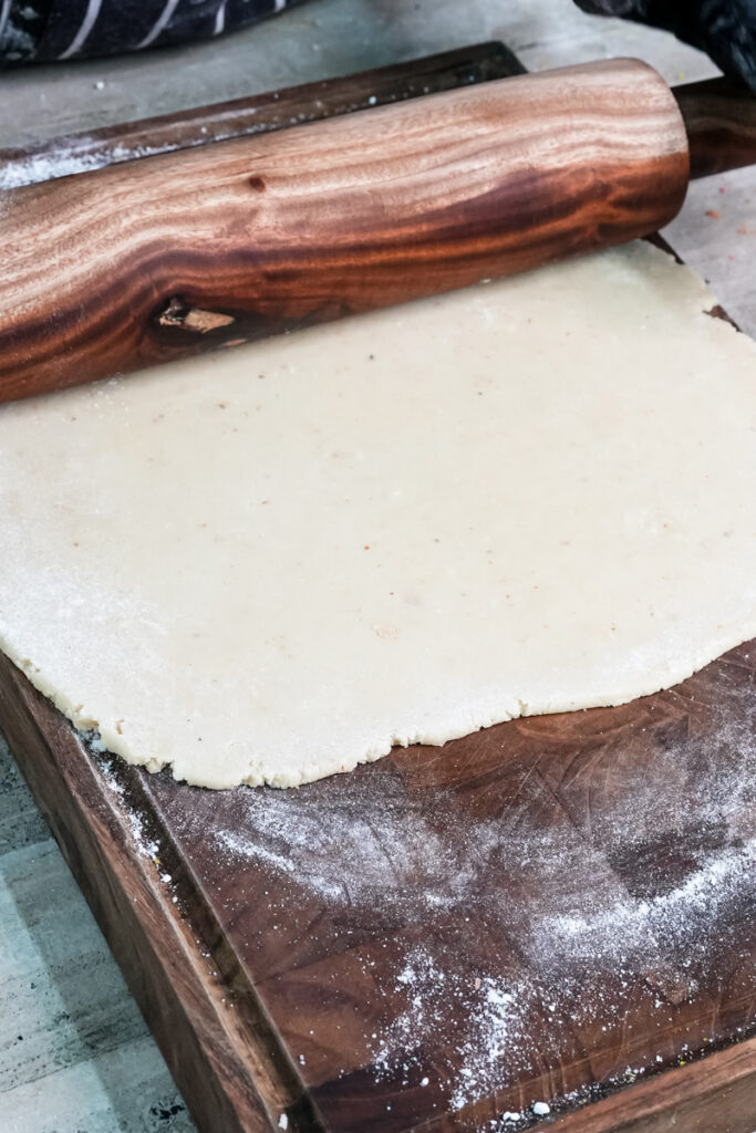 Rolling marzipan for Battenberg cake wrapping with wooden rolling pin