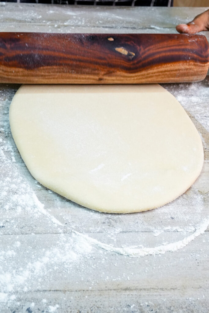 Rolling out empanada dough with wooden rolling pin