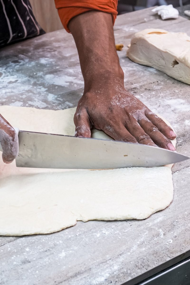Rolling out kouign amann dough on floured surface