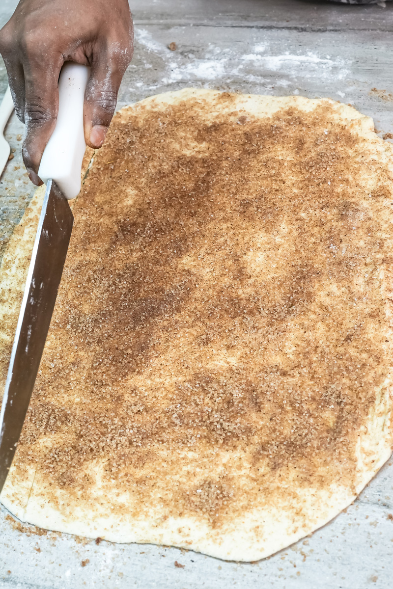 Rolling pin pressing cinnamon sugar into pastry dough
