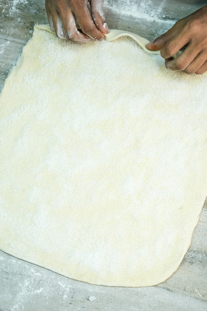 Rolling puff pastry dough for palmiers on floured surface