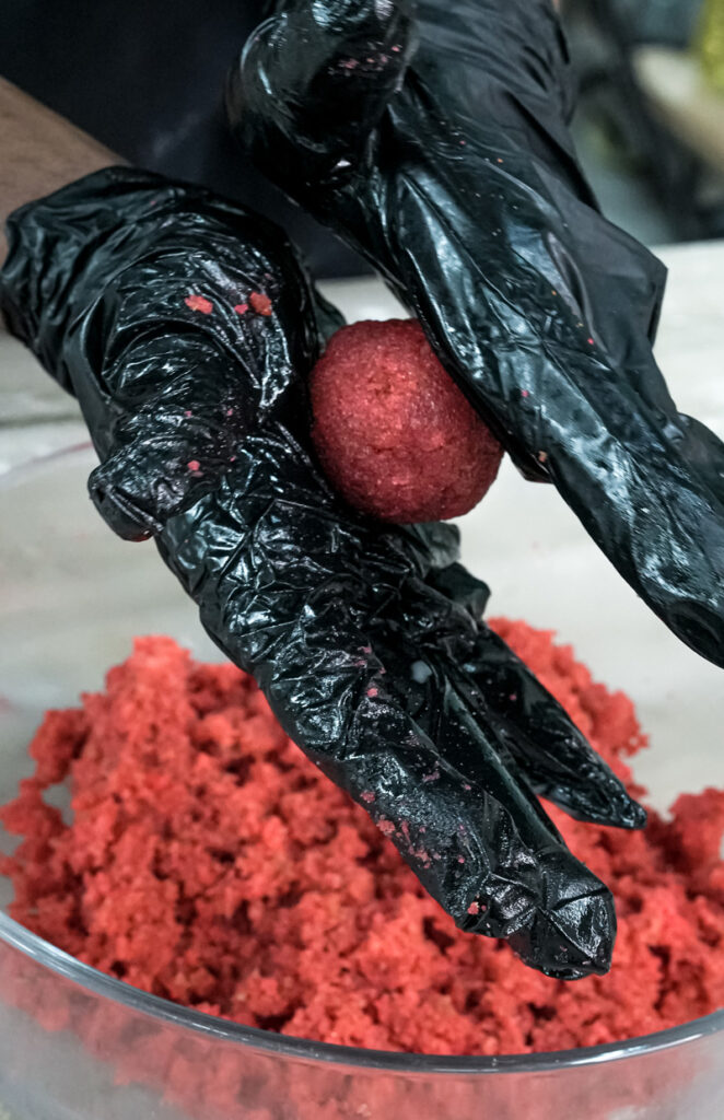 Rolling strawberry cake pop mixture into balls by hand