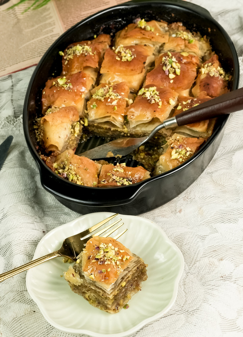 Served baklava slice with full pan in background