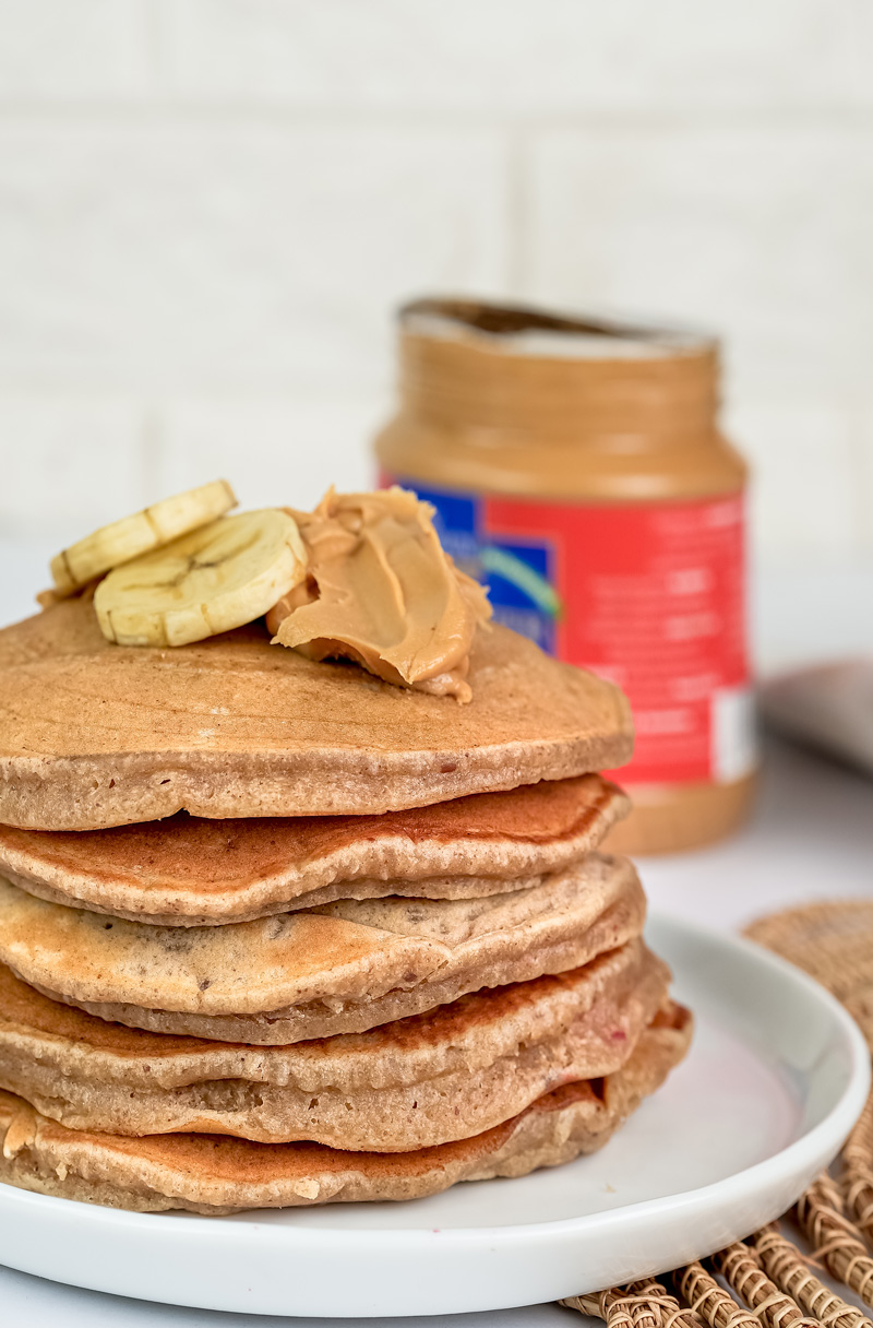 Side view of layered peanut butter pancakes with banana garnish