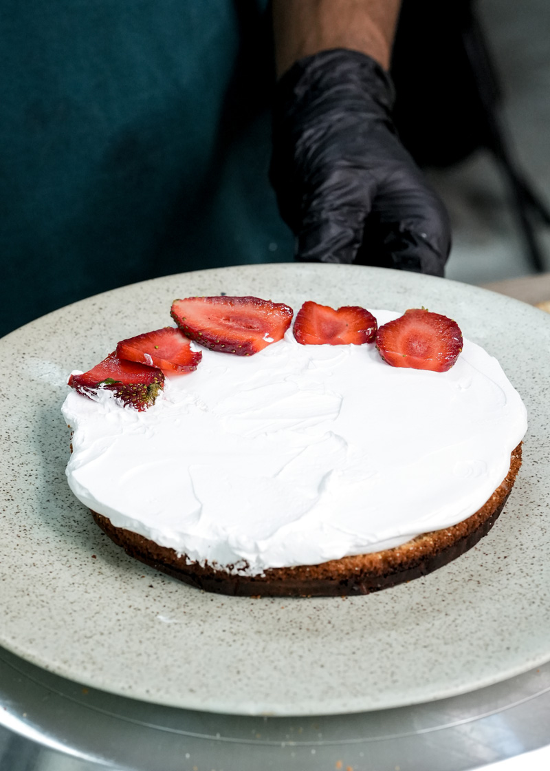 Single layer sponge cake topped with whipped cream and sliced strawberries
