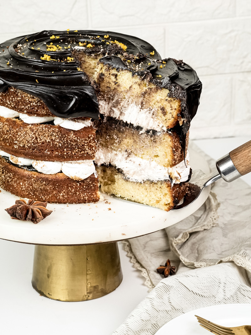 Slicing churro layer cake showing white cream filling and chocolate ganache topping