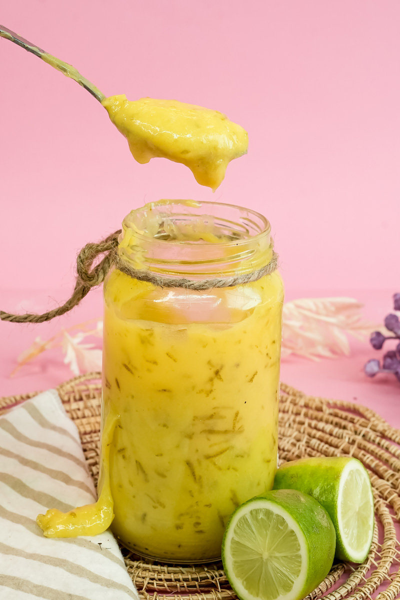 Spoonful of homemade lemon curd dripping from jar
