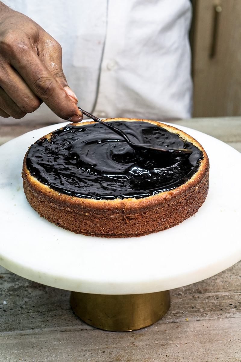 Spreading chocolate ganache on churro cake layer with offset spatula