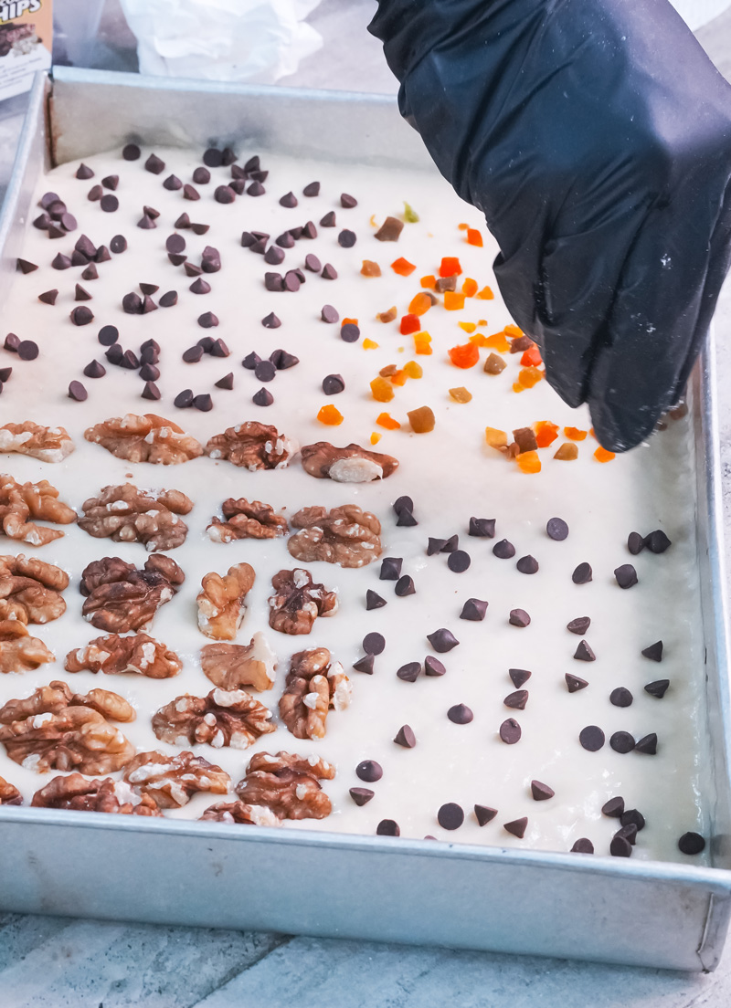 Sprinkling chocolate chips and dried fruit on sheet pan pancakes