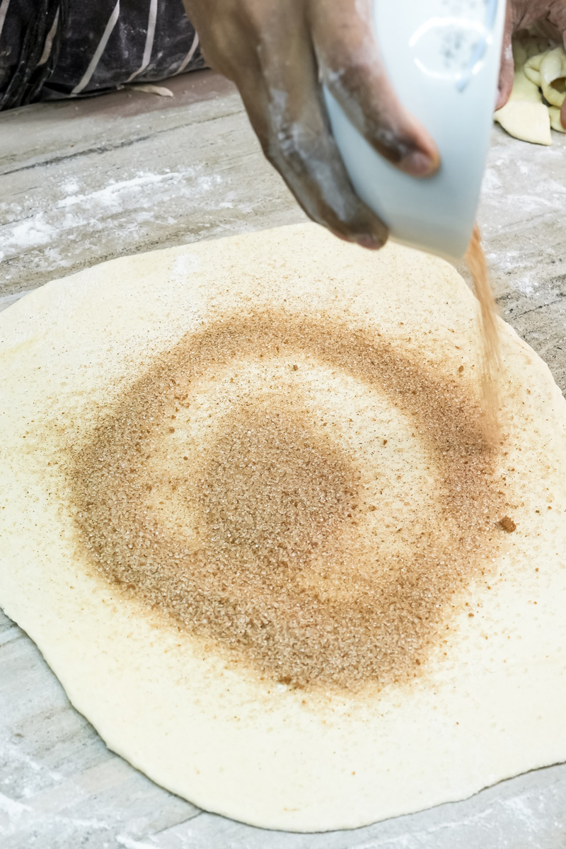 Sprinkling cinnamon sugar mixture onto pastry dough