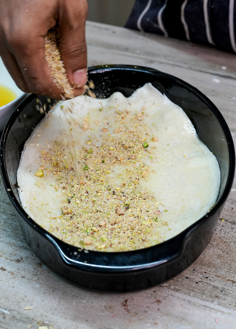 Sprinkling pistachio mixture over phyllo dough layers