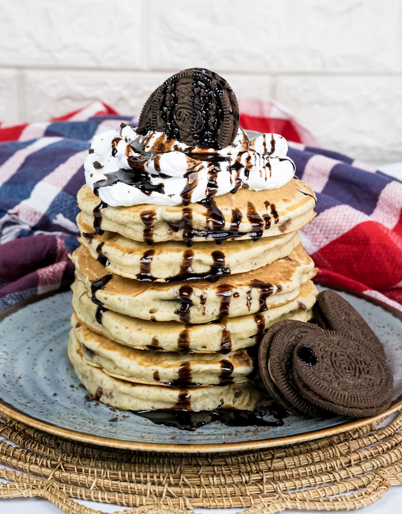 Stack of fluffy Oreo pancakes with chocolate syrup and whipped cream topping
