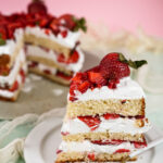 Strawberry shortcake slice with fork and whole cake in background