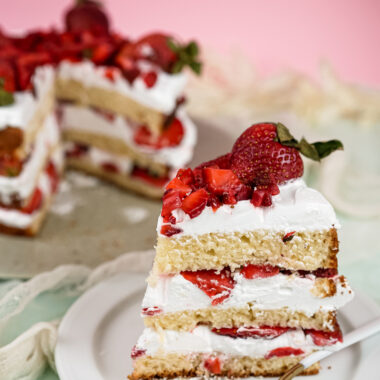 Strawberry shortcake slice with fork and whole cake in background