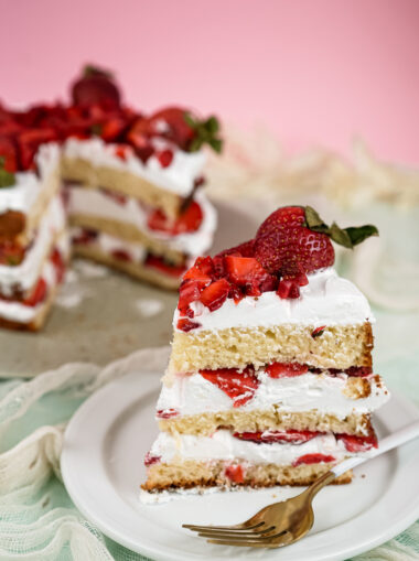 Strawberry shortcake slice with fork and whole cake in background