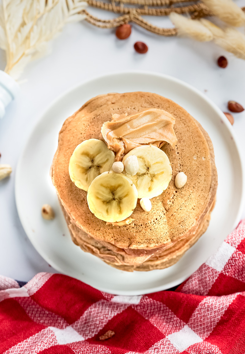 Top view of peanut butter pancake with banana and peanut garnish