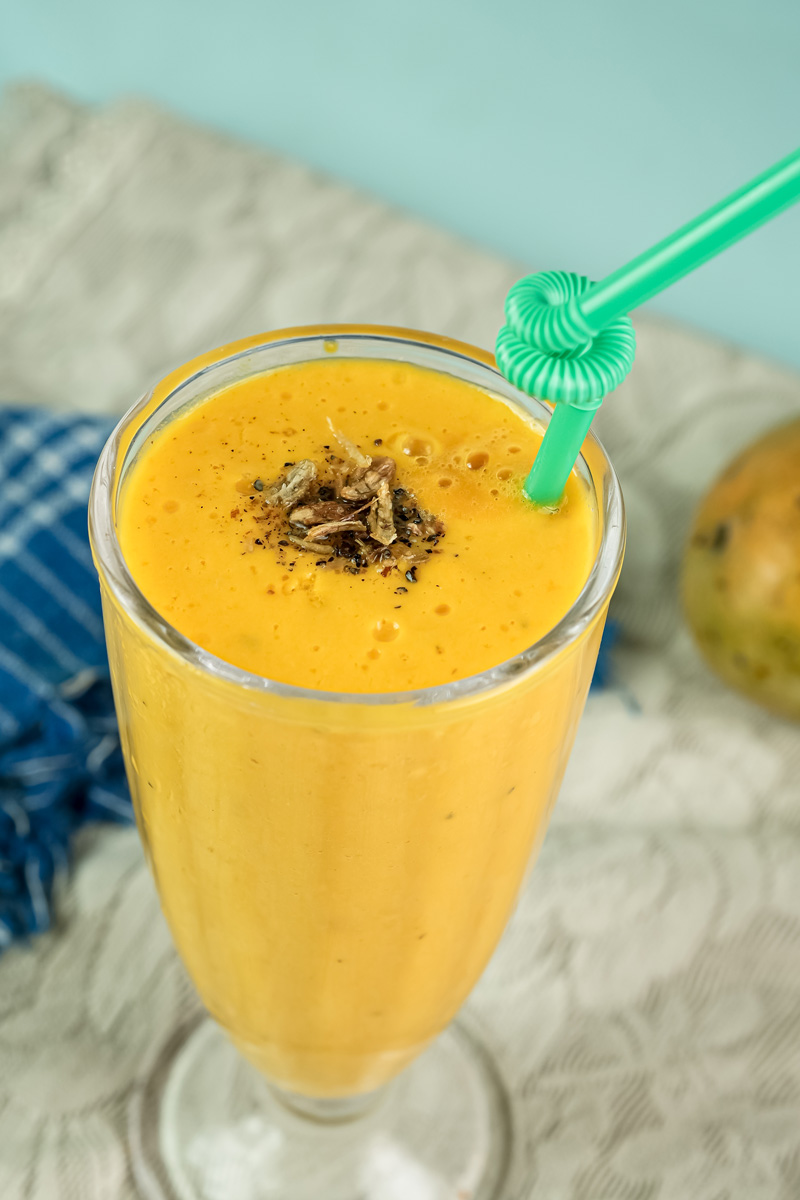 Top view of mango lassi with straw and spice garnish