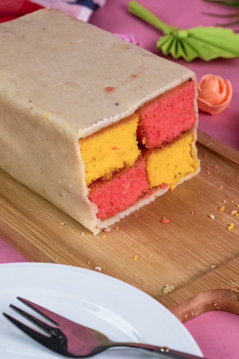 Traditional Battenberg cake with marzipan wrapping on wooden cutting board