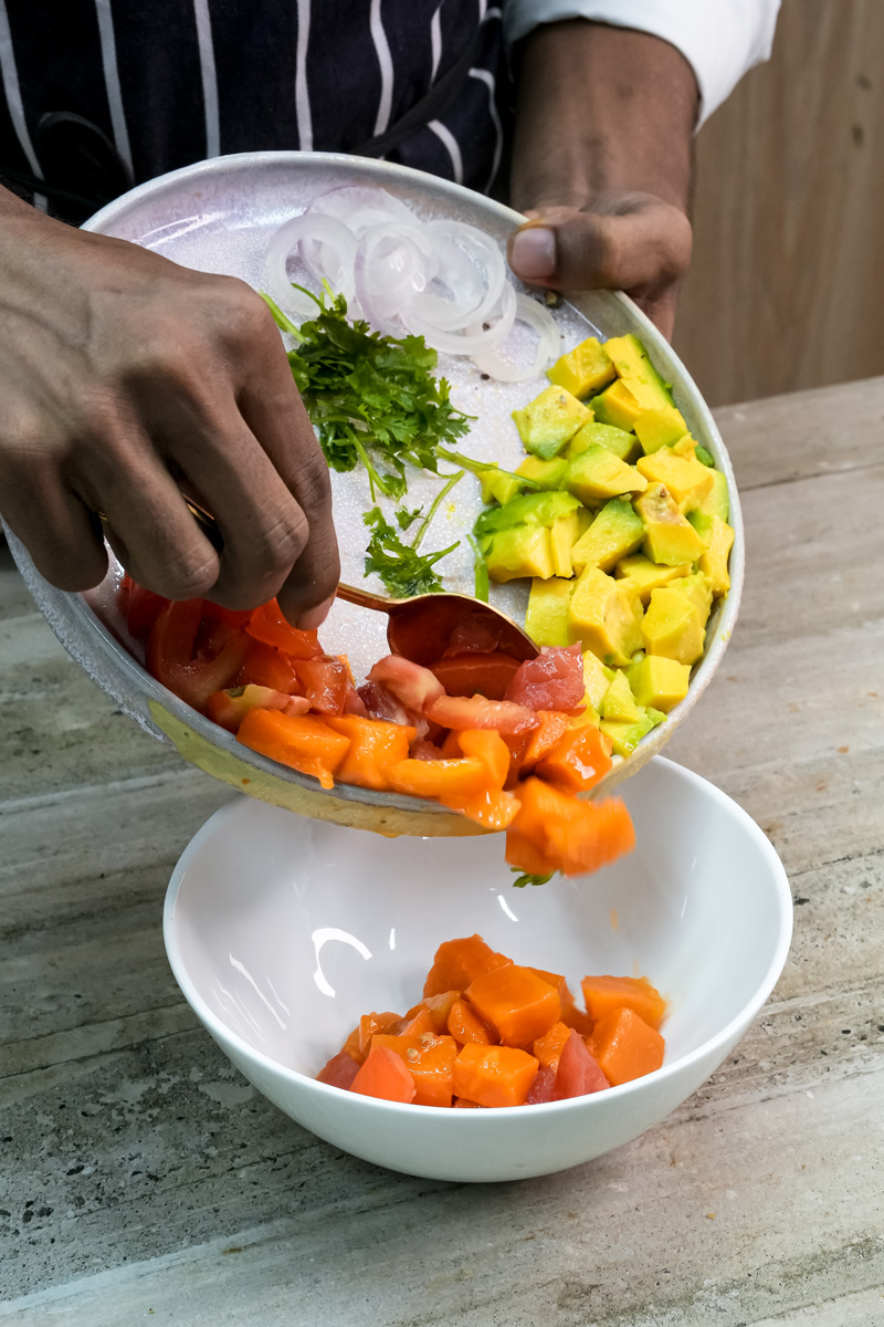 Transferring diced mango avocado salad ingredients into mixing bowl
