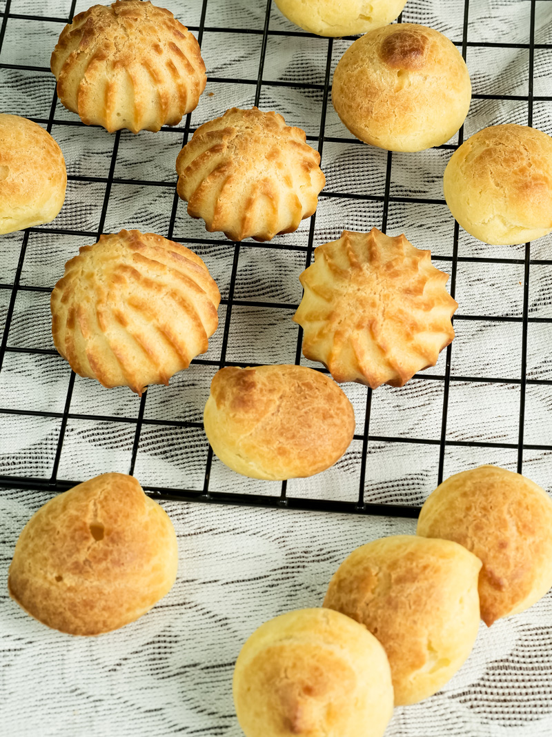 Various shaped baked choux pastry cooling on wire rack