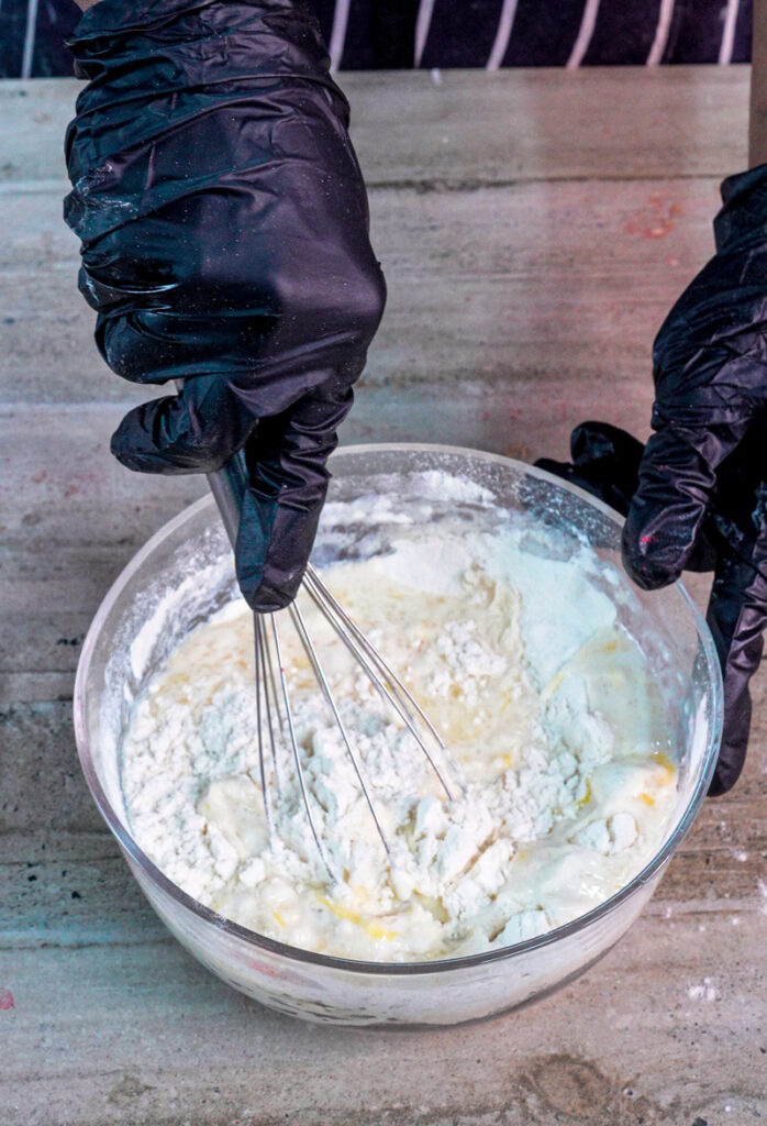 Whisking cinnamon roll pancake batter with wire whisk in glass bowl