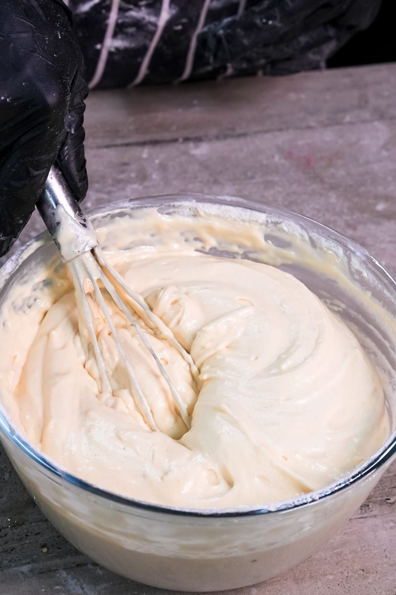Whisking smooth ladyfinger cookie batter in glass bowl