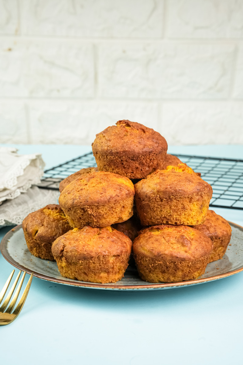 Stack of freshly baked golden mango muffins on serving plate