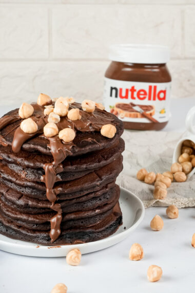 Tall stack of chocolate Nutella pancakes with nuts
