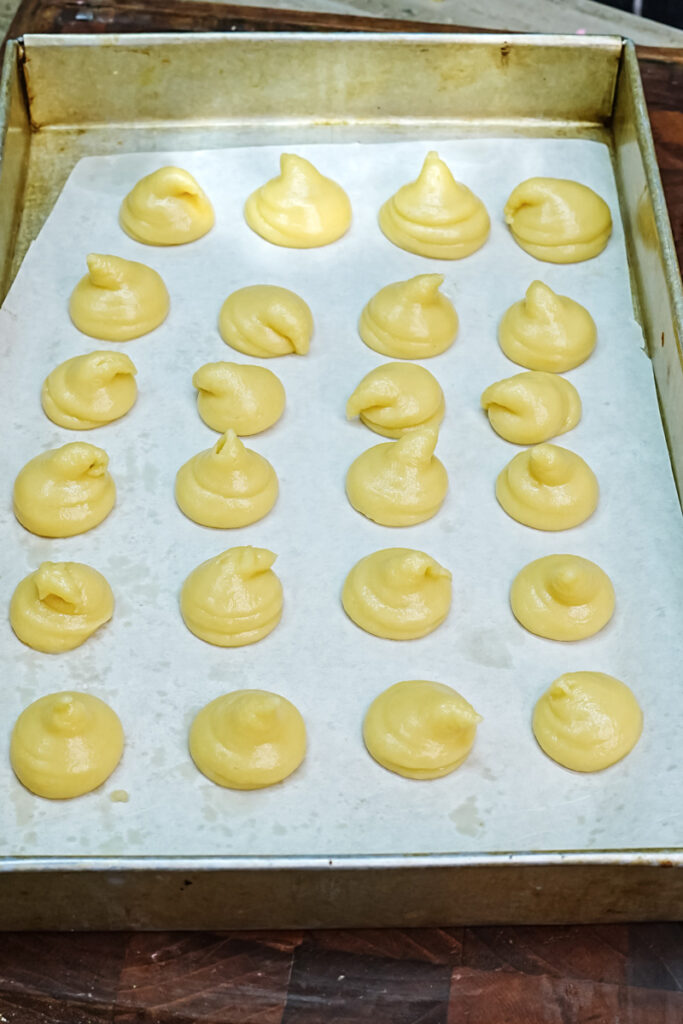 Unbaked choux pastry portions arranged on parchment paper