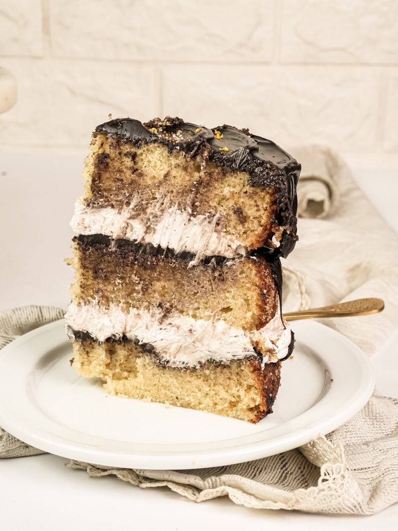 Single slice of churro cake on white plate with gold fork showing layered interior