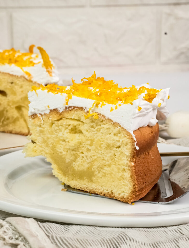 Individual citrus cake slice on white plate with orange zest